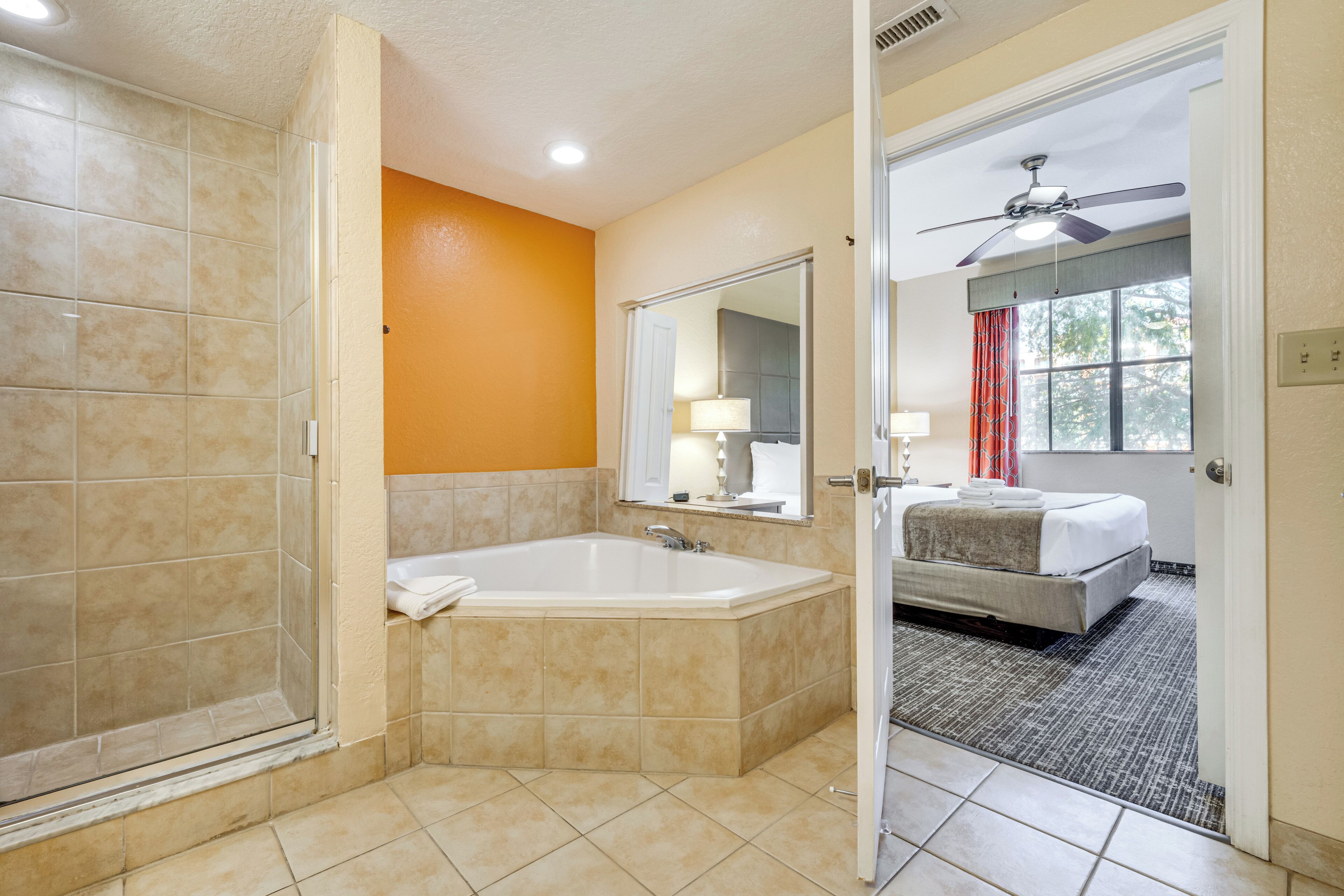 Une salle de bain d’hôtel avec douche, baignoire et grand miroir.