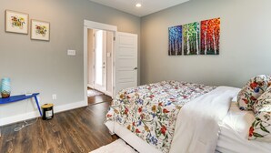 Une chambre à coucher comprenant un lit, un bureau et une porte donnant sur une autre pièce.