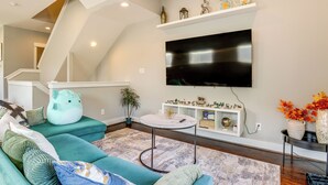 Un salon moderne avec des canapés de couleur turquoise, un téléviseur à écran plat et des étagères décoratives.