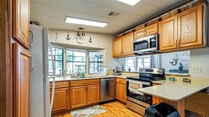 A kitchen with wooden cabinets, stainless steel appliances, and a window providing natural light. - Angler's Paradise! Homosassa River Retreat w/ Dock (Homosassa)