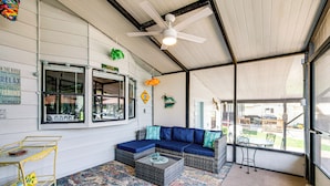 A covered outdoor seating area with a blue sofa, wicker furniture, and a colorful rug. - Angler's Paradise! Homosassa River Retreat w/ Dock (Homosassa)