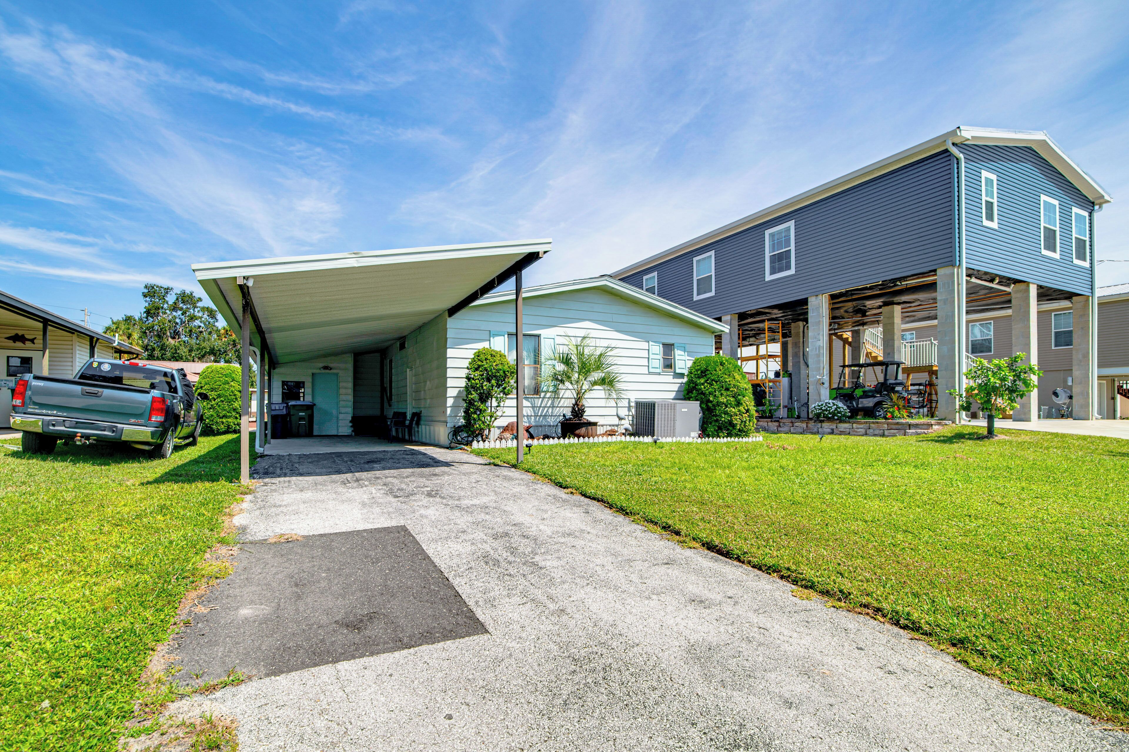 A residential house with a covered garage, a driveway, and a lawn.