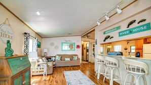 A cozy living room with a wooden floor, a sofa, a coffee table, and a bar area with stools. - Angler's Paradise! Homosassa River Retreat w/ Dock (Homosassa)