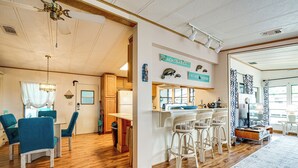 A spacious kitchen with wooden cabinets, a dining area with blue chairs, and a bar area with white stools. - Angler's Paradise! Homosassa River Retreat w/ Dock (Homosassa)