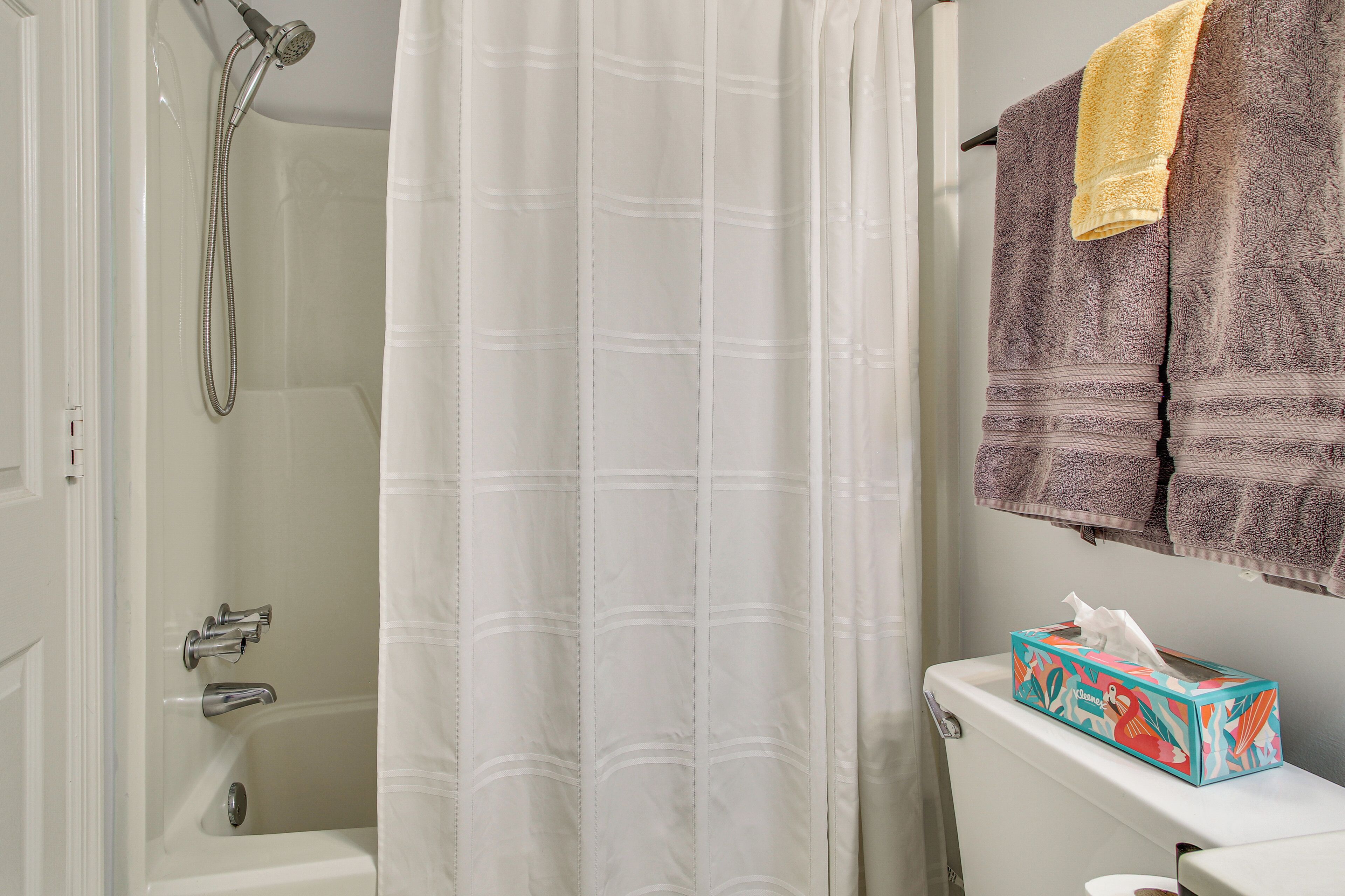 A bathroom with a shower curtain, a toilet, and a towel rack with towels.