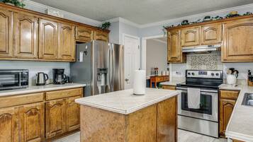 A kitchen with wooden cabinets, stainless steel appliances, a marble countertop, and a tiled backsplash.