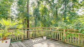 Una terrazza in legno con ringhiera, circondata da vegetazione lussureggiante.
