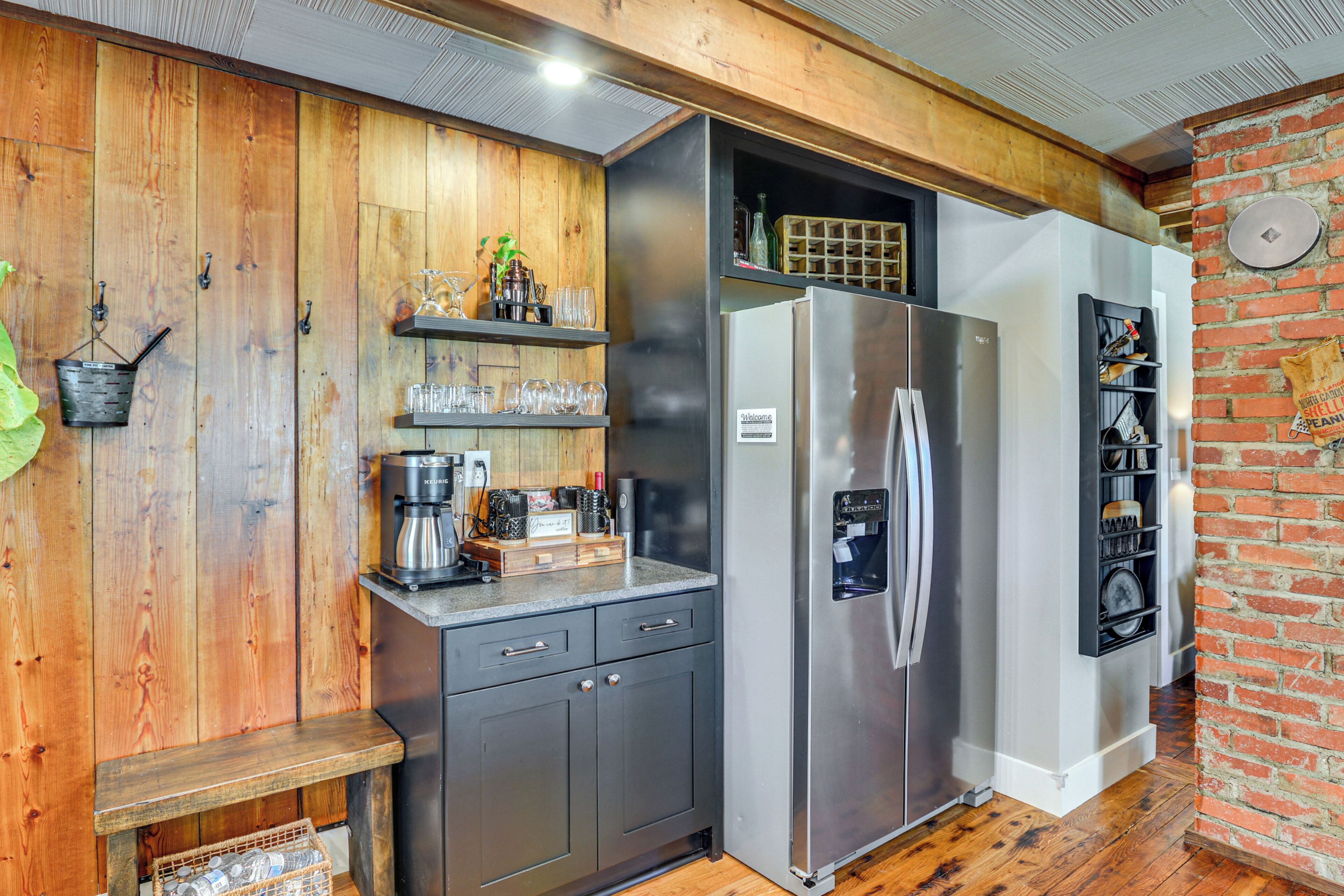 A compact kitchen with wooden walls, a stainless steel refrigerator, and a built-in wine rack.