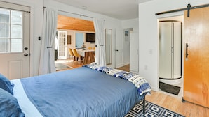 A bedroom with a bed, a wooden ceiling fan, a sliding door, and a view into a dining area. - Ice Fish, Snowshoe & Ski: Group Getaway in Summit (Summit)