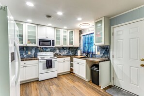 A compact kitchen with white cabinets, a microwave, an oven, and a sink. - 6 Mi to Dtwn Pensacola: Family-friendly Gem! (Pensacola)