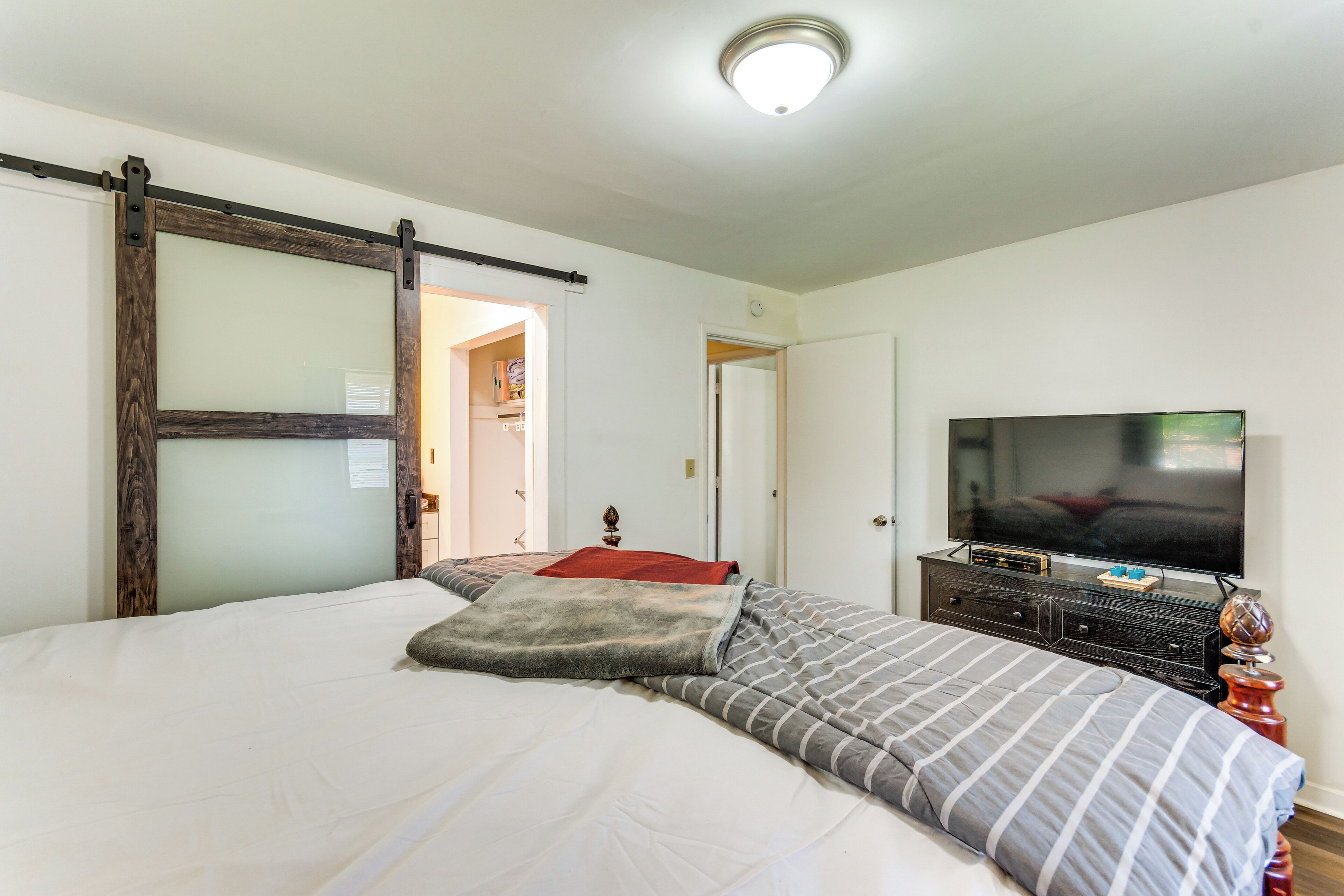 A bedroom with a bed, a television, a dresser, and a sliding door.