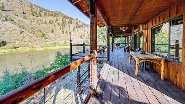 A wooden deck with a view of a river and hills. - Hike, Fish & Unwind: Remote Escape in Montana (St. Regis)