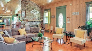 A spacious living room with a fireplace, comfortable seating, and a kitchen in the background. - Private Hot Tub! Home < 1 Mi to Lake Okeechobee (Okeechobee)