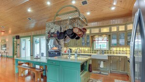 A kitchen with wooden cabinets, a central island, and hanging pots. - Private Hot Tub! Home < 1 Mi to Lake Okeechobee (Okeechobee)