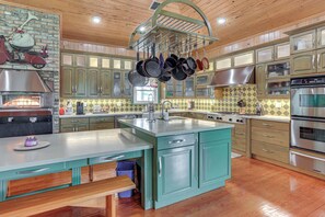 A kitchen with wooden cabinets, a central island, hanging pots, a built-in oven, and a window. - Private Hot Tub! Home < 1 Mi to Lake Okeechobee (Okeechobee)