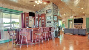 A bar area with wooden bar stools and a television mounted on the wall. - Private Hot Tub! Home < 1 Mi to Lake Okeechobee (Okeechobee)
