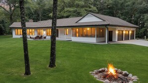 A modern two-story house with a well-maintained lawn, a fire pit, and a garage.