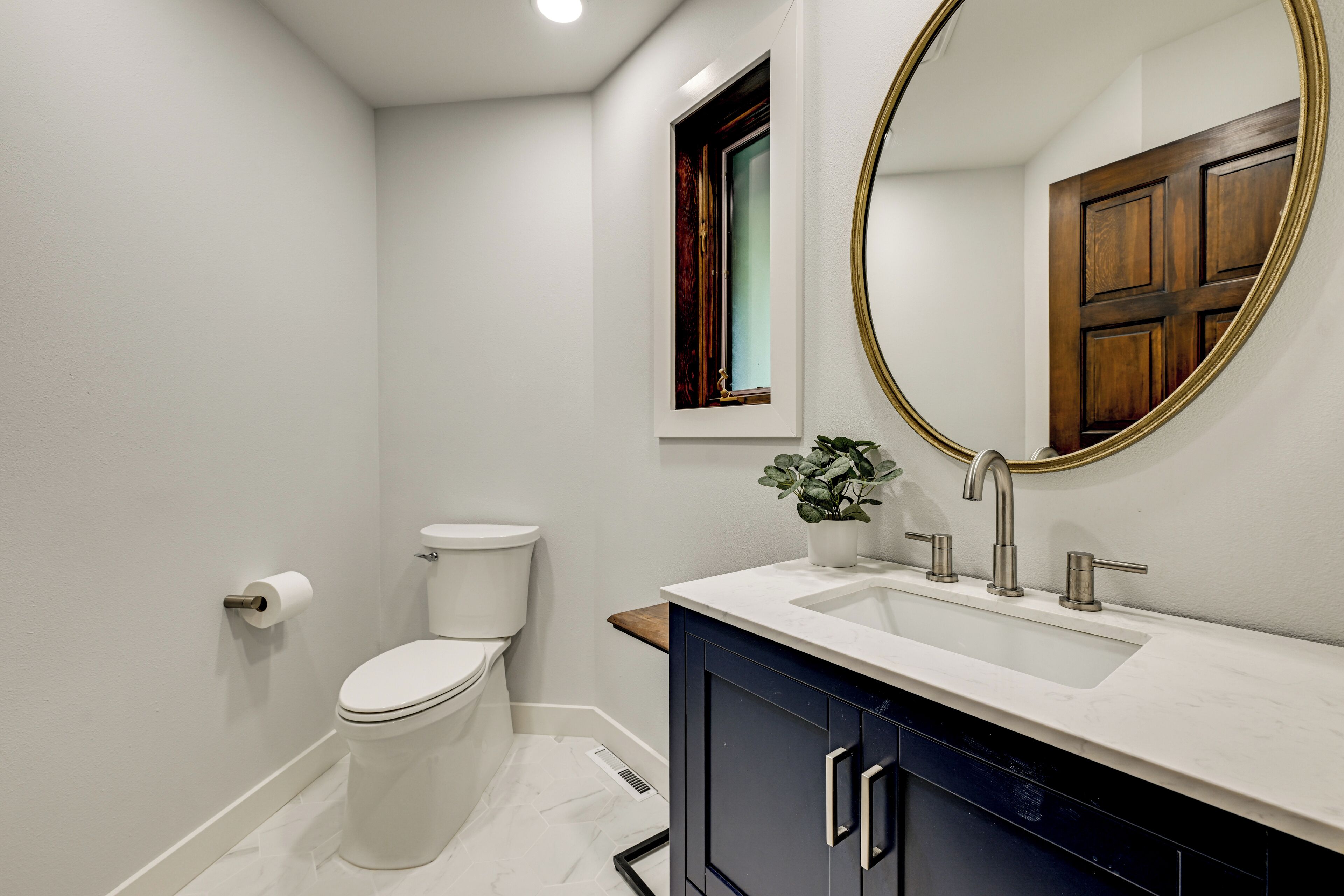 A bathroom with a toilet, sink, and mirror.