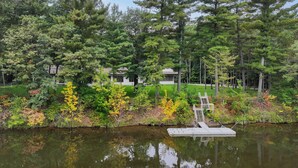 A lakeside property with a dock, surrounded by dense trees and a well-maintained lawn.
