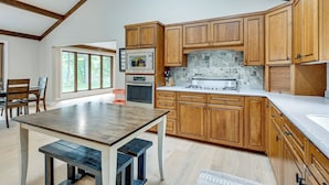 A spacious kitchen with wooden cabinets, a large island, and a stone backsplash.