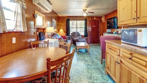 A wooden interior with a dining table, chairs, a sofa, a television, and a microwave. - Walk to Greers Ferry Lake! Home w/ Dock Access (Higden)