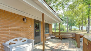 A covered porch with a brick wall, a white bench, and a grill area. - Walk to Greers Ferry Lake! Home w/ Dock Access (Higden)