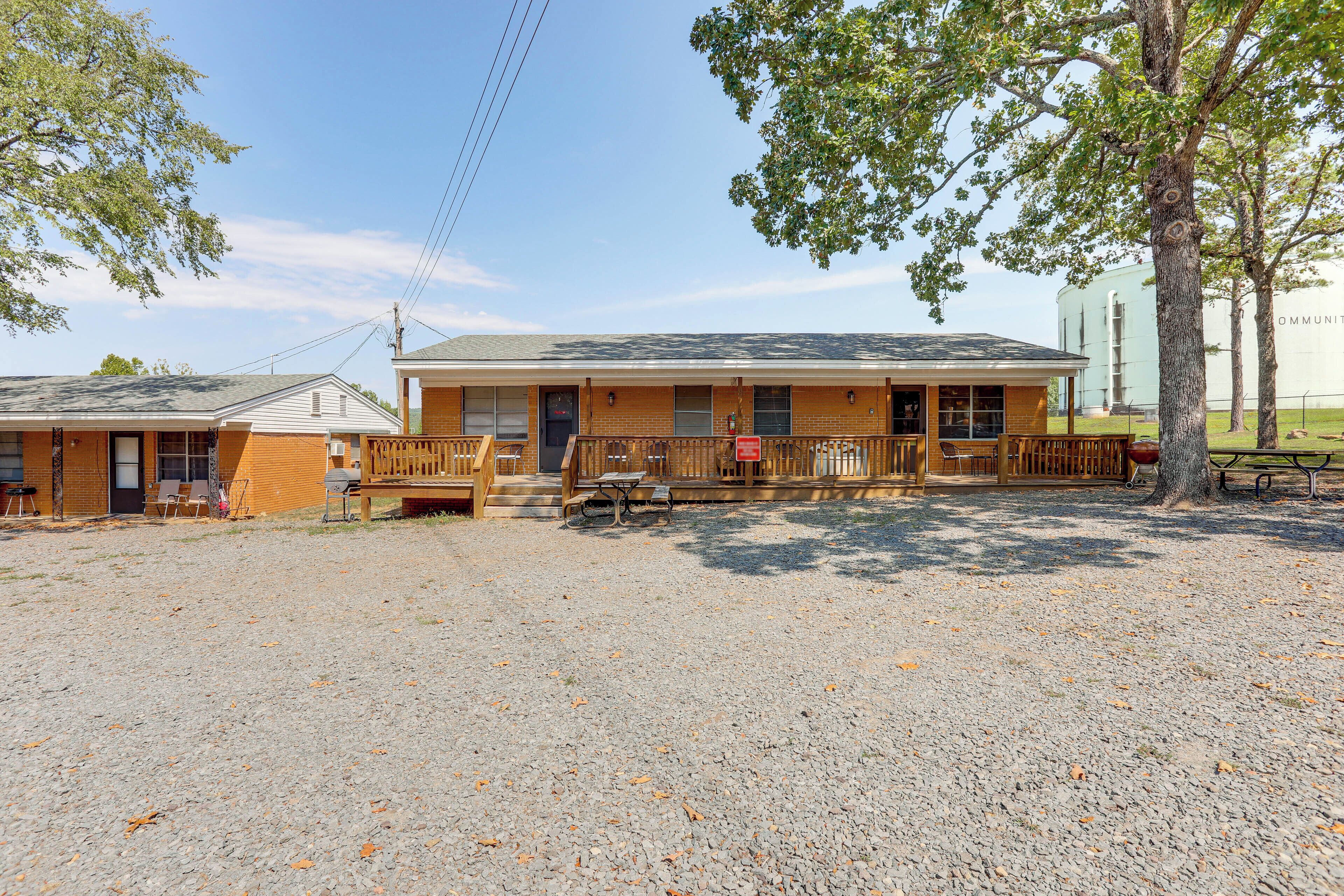 A motel with a covered front porch, outdoor seating, and a gravel parking area.