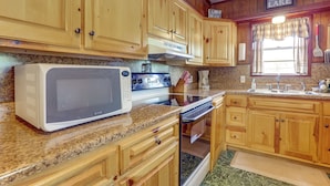 A kitchen with wooden cabinets, a microwave, stove, and a sink. - Walk to Greers Ferry Lake! Home w/ Dock Access (Higden)