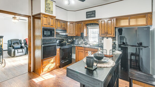 A modern kitchen with wooden cabinets, a large island, and a ceiling fan. - Close to Hospital & Dtwn! Quiet Waycross Home (Waycross)