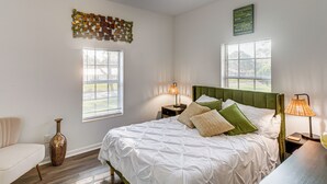 A bedroom with a bed, two bedside tables, a nightstand, a decorative wall piece, and a window with blinds. - Close to Hospital & Dtwn! Quiet Waycross Home (Waycross)