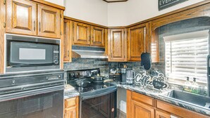 A kitchen with wooden cabinets, a black stove, a microwave, and a coffee maker. - Close to Hospital & Dtwn! Quiet Waycross Home (Waycross)