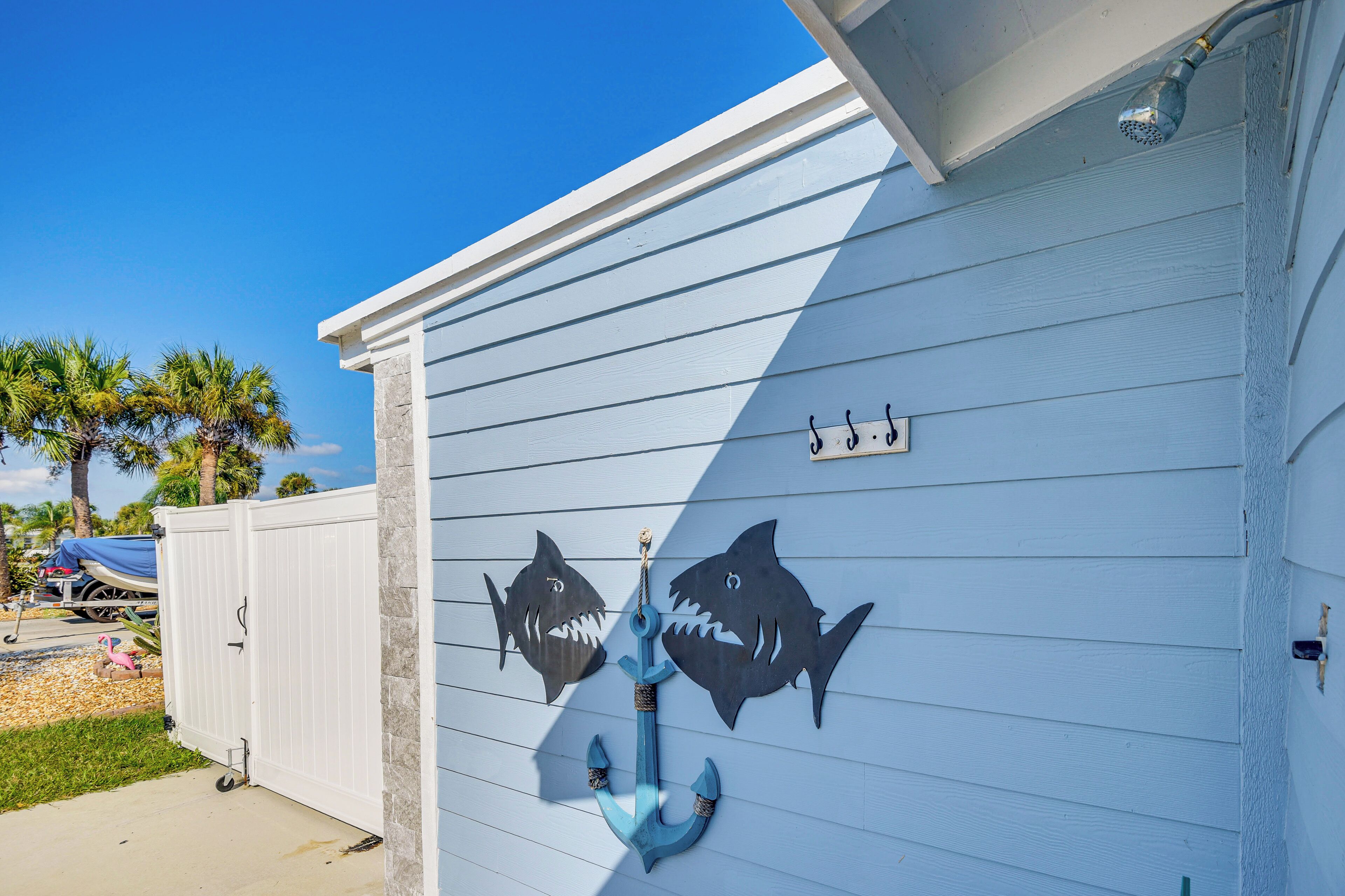 Et hus med lyseblå facade, hvid garageport og et dekorativt anker med hajsilhuetter.