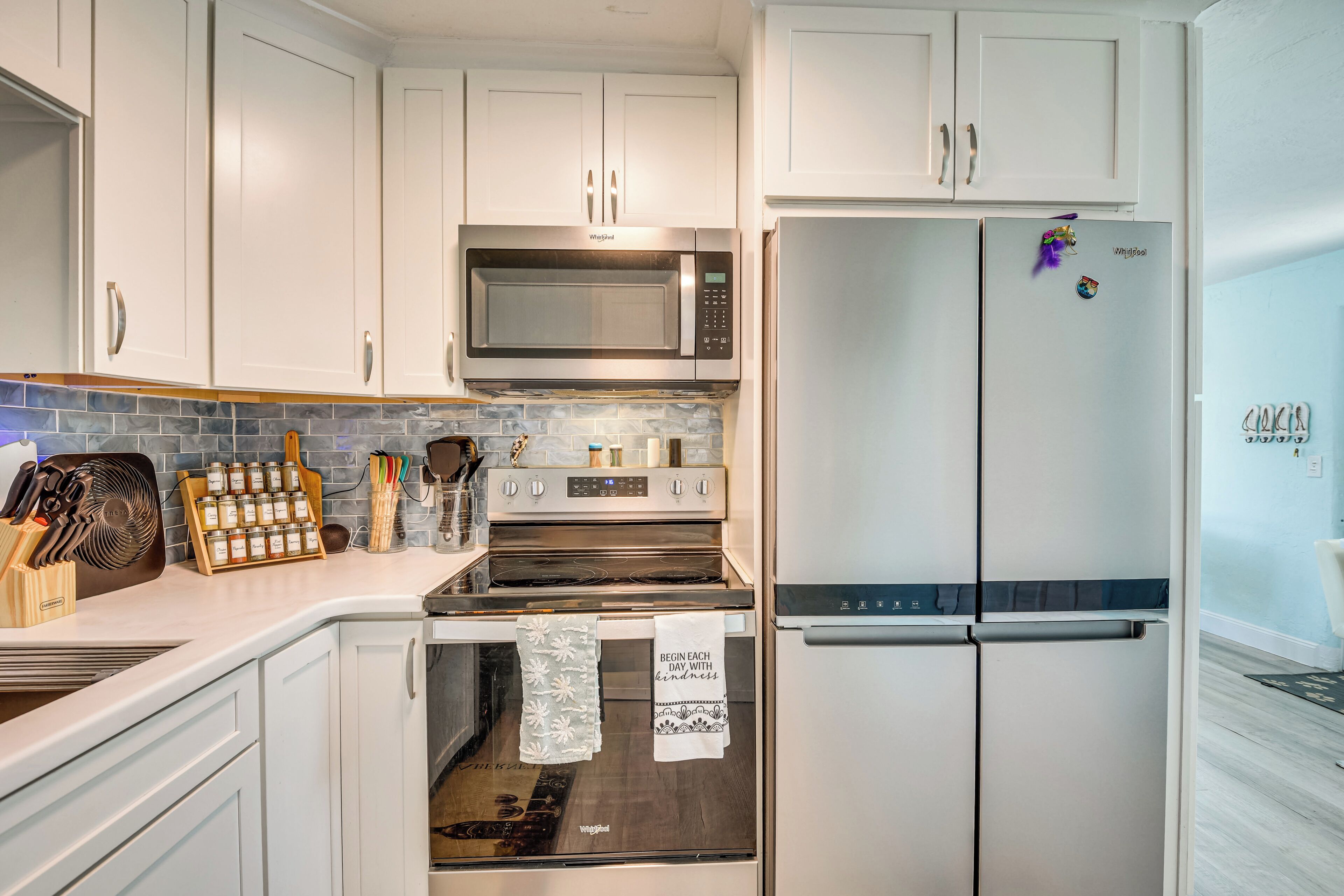 A modern kitchen with white cabinetry, a built-in microwave, a stainless steel refrigerator, and a stove.