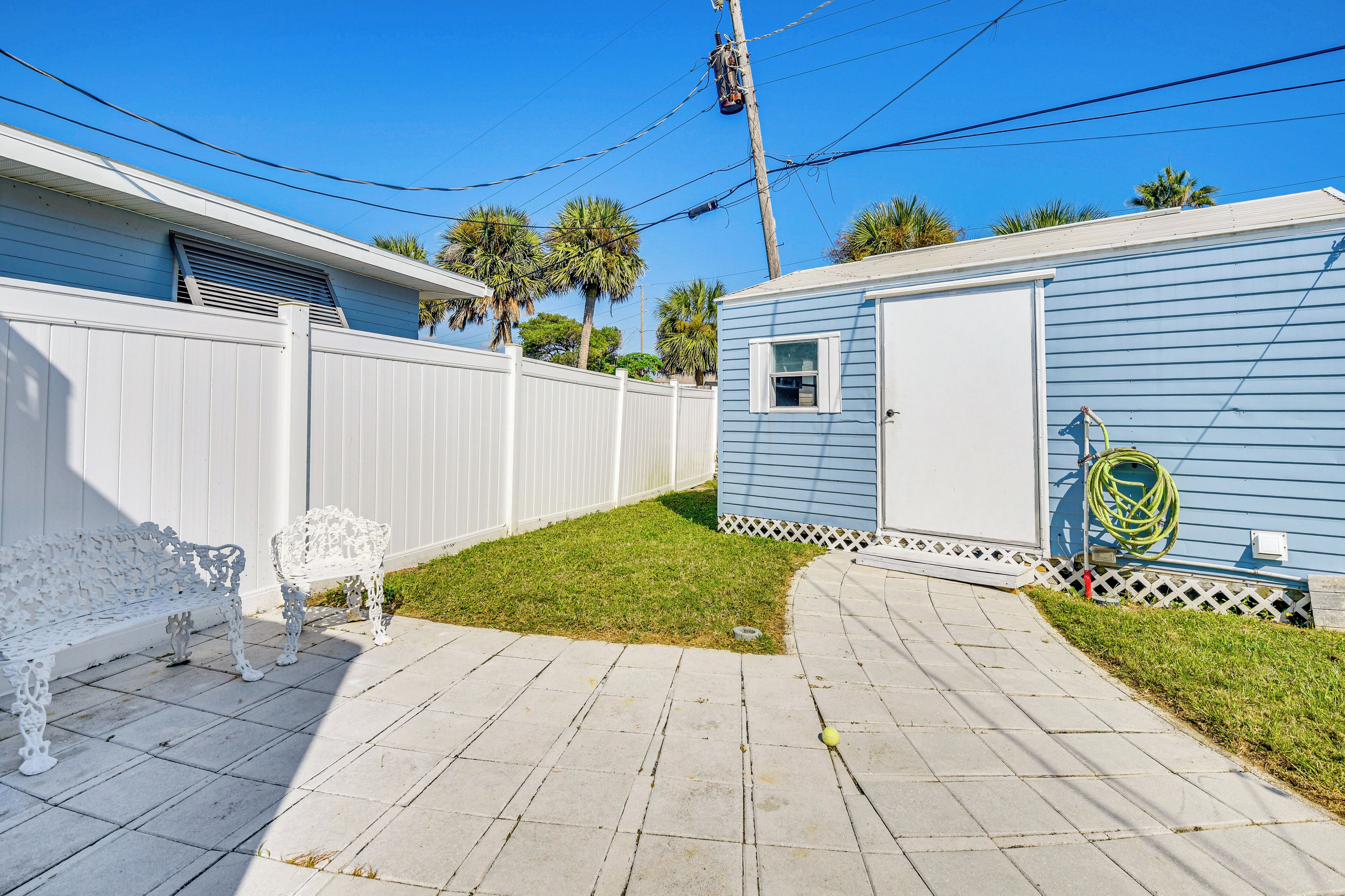 A backyard with a white bench, a small shed, and a lawn.