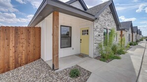 Une rangée de maisons modernes, avec une clôture en bois, un chemin de gravier et un ciel dégagé.