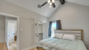 Une chambre à coucher avec un lit, un ventilateur de plafond et une fenêtre avec des rideaux.