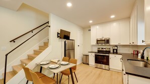 A modern kitchen with white cabinets, stainless steel appliances, and a dining area with a table and chairs.
