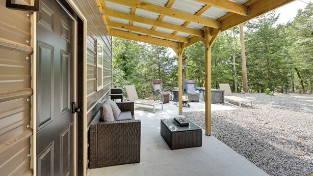 A covered outdoor patio with wicker furniture, a concrete floor, and a gravel area.