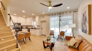A modern living room with a staircase, a dining area, and a kitchen.