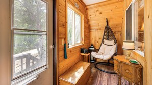 Ein Holzblockhaus-Interieur mit Schaukelstuhl, Bank und einem kleinen Tisch mit Lampe.