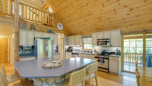 A spacious kitchen with a central island, wooden cabinets, and a stone base. - Port Austin Cabin w/ Hot Tub: 1 Mi to Beach! (Port Austin)