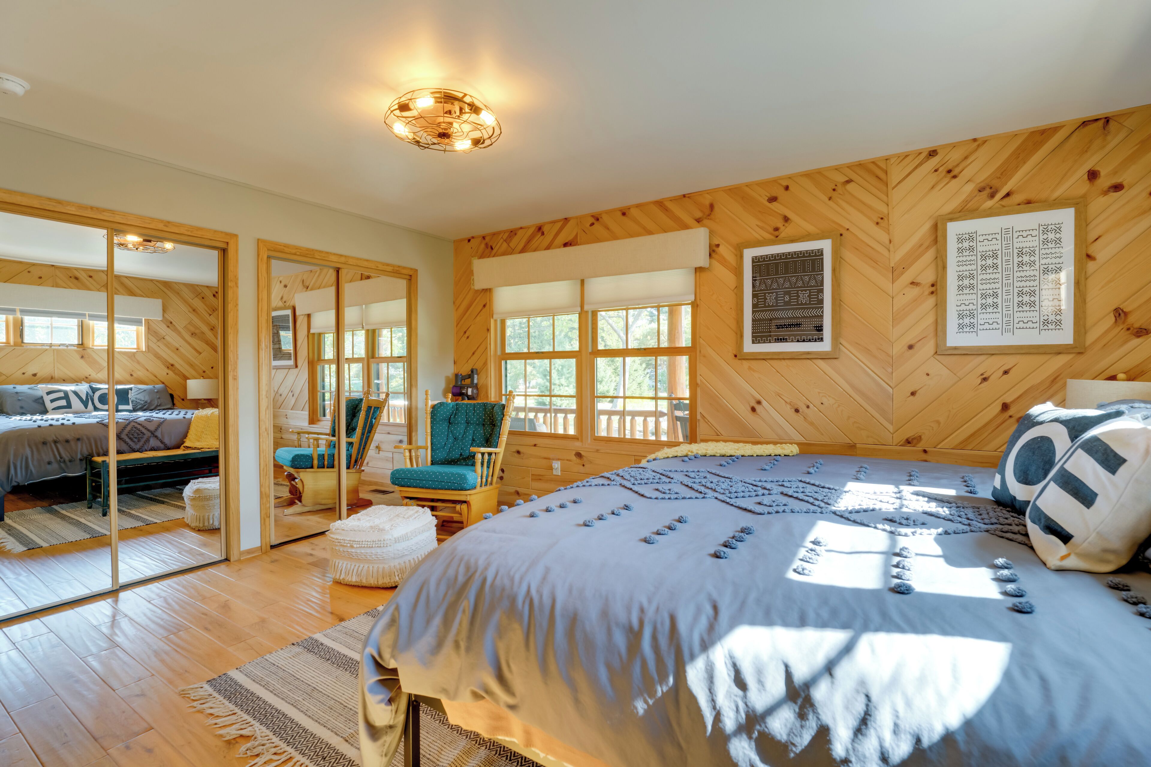 A bedroom with a large bed, wooden walls, and a view through a glass door.