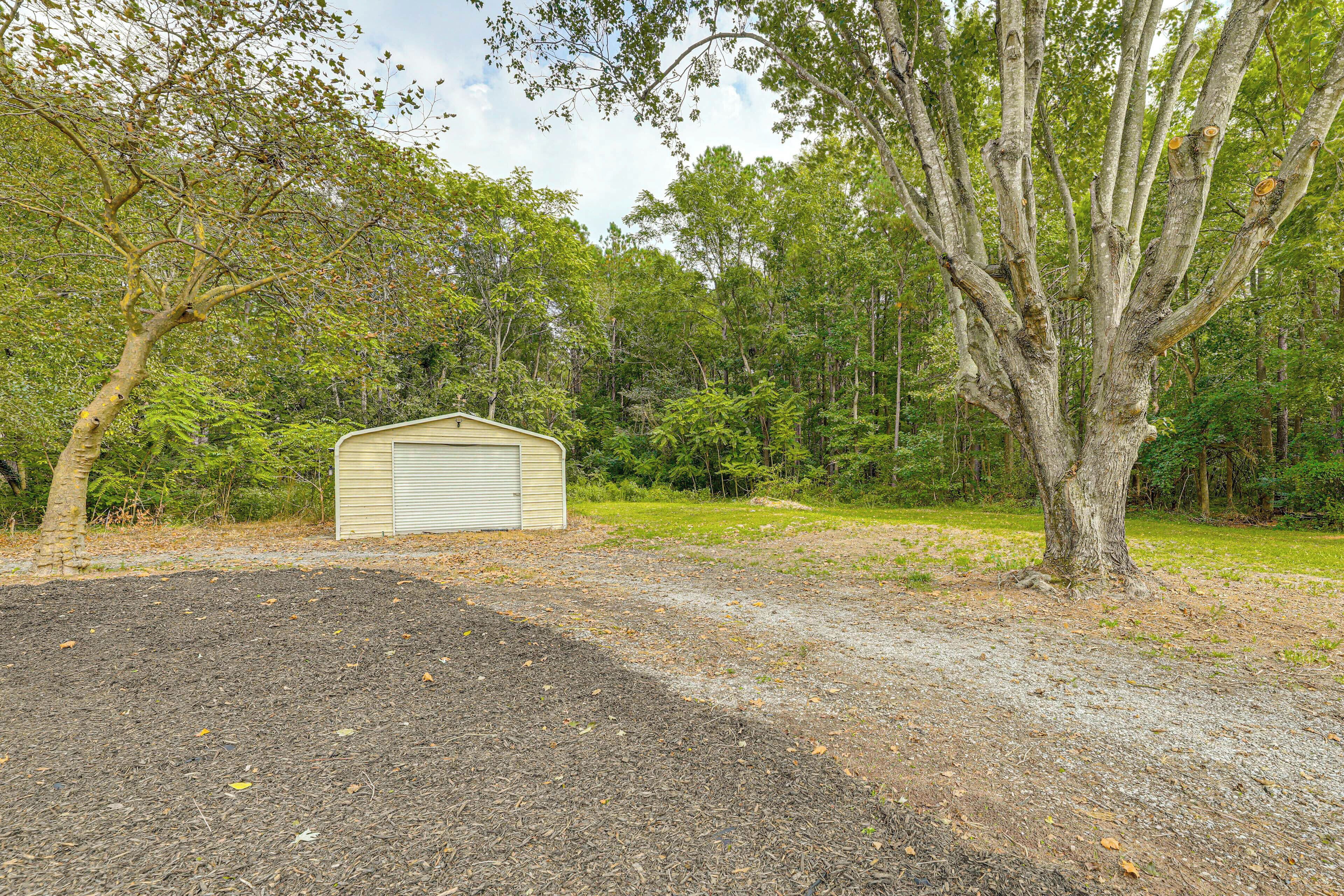 A single-story building with a flat roof, surrounded by a gravel driveway and a large tree.