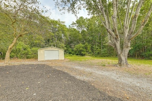 A single-story building with a flat roof, surrounded by a gravel driveway and a large tree. - Pet-friendly Home: Fire Pit & Winter Escape (Lincoln)