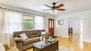 Ein Wohnzimmer mit einem braunen Sofa, einem dunklen Holztisch und einem Deckenventilator.
