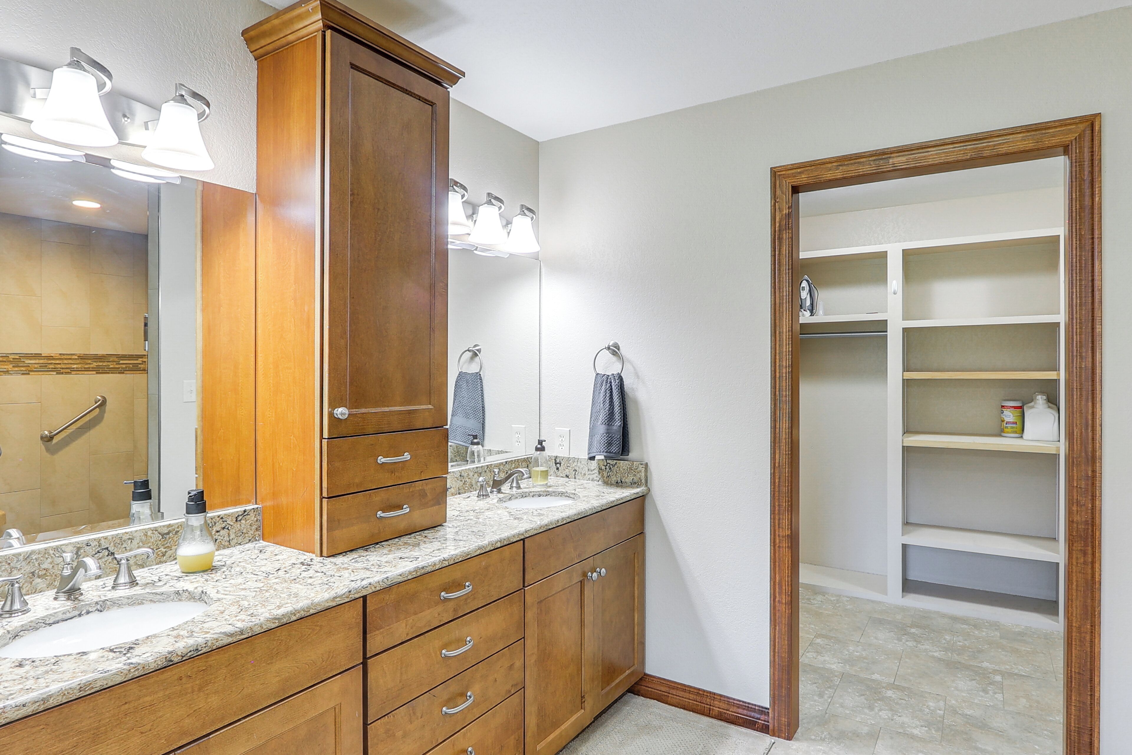 A bathroom with wooden cabinets, a double sink, and a large mirror.