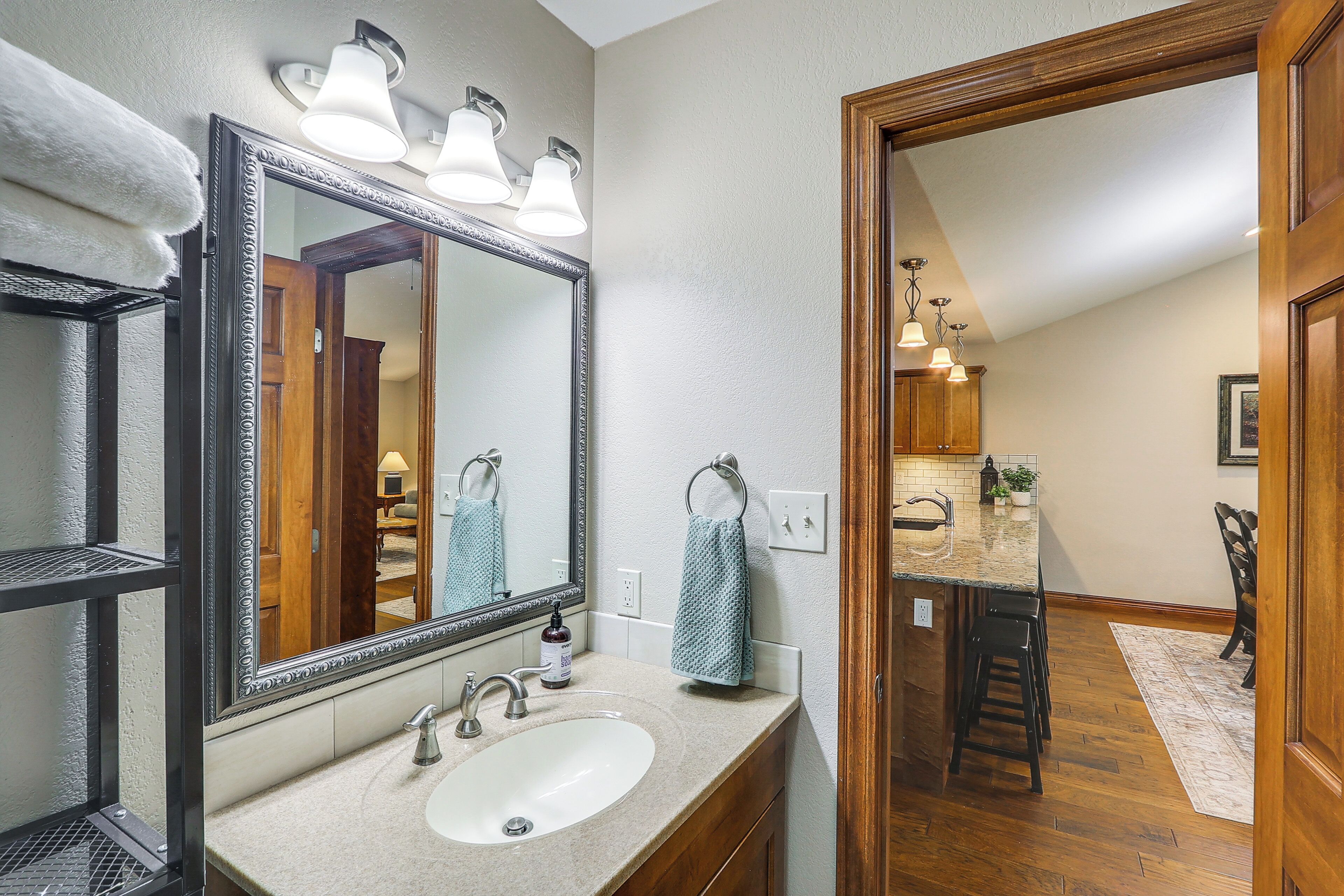 A bathroom with a large mirror, a sink, and a towel rack.