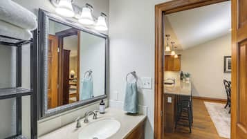 A bathroom with a large mirror, a sink, and a towel rack.