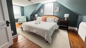 Un dormitorio con cama, ventilador de techo, mesita de noche, lámpara, silla y ventana con persianas.