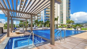 Un espace piscine sur le toit, doté d’une terrasse en bois, d’un jacuzzi et de chaises longues.